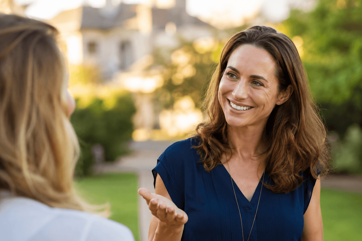 A woman warmly recommending a trusted pro to a friend outdoors.